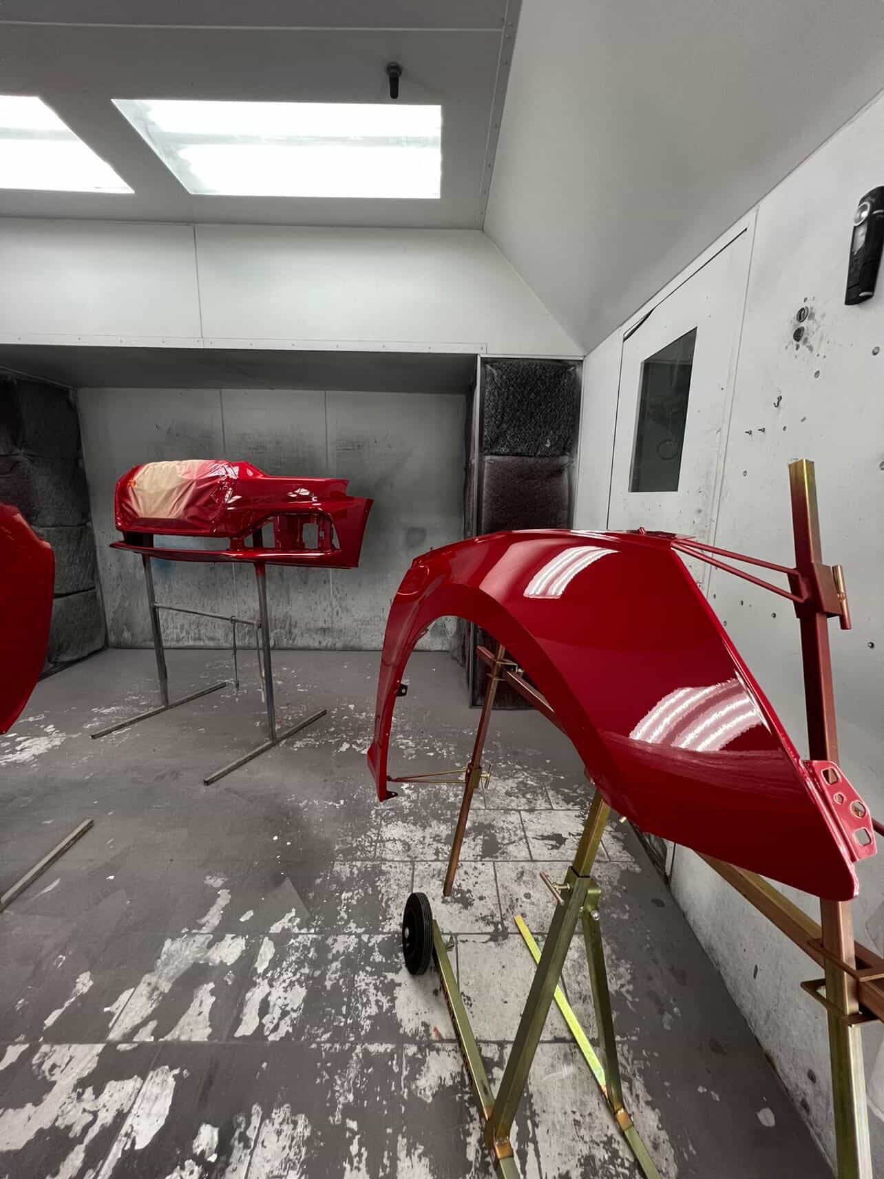 Red body panel in the paint booth during refinishing